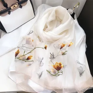 Detailed embroidery of yellow magnolia flowers and grey butterflies on white silk scarf