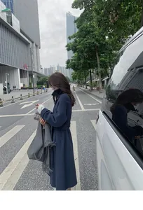 Elegant grey oversized warm tassel shawl held by a model in a modern urban street setting