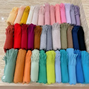 Macro view of multiple colorful solid scarves with fringes arranged neatly on a surface