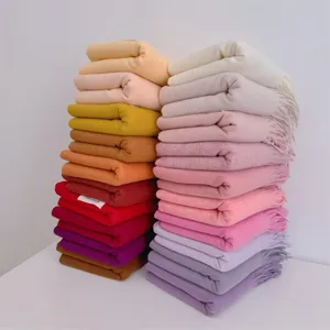 Stack of colorful soft wool winter scarves with fringe tassels in a variety of colors