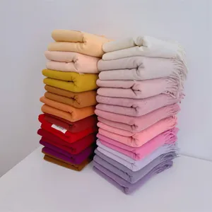 Detailed view of warm fringed pashmina scarves in various solid colors for winter.