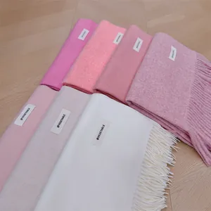 Macro view of several soft solid color winter scarves with tassels and small white labels