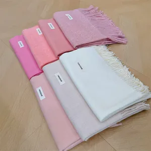 Close-up detailed view of soft winter scarves with tassels in various pastel colors