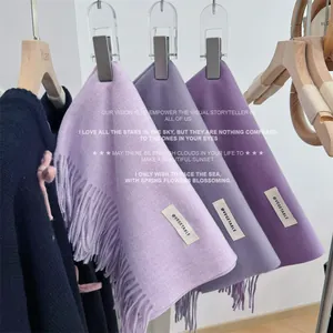 Trio of soft purple fringed scarves in lavender and mauve shades hanging on a rack