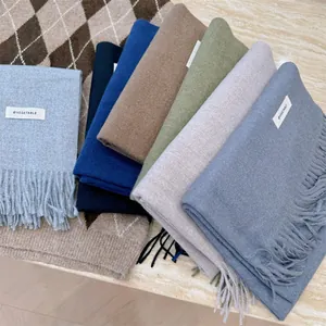 Detailed view of various soft winter scarves in multiple colors with tassels and labels