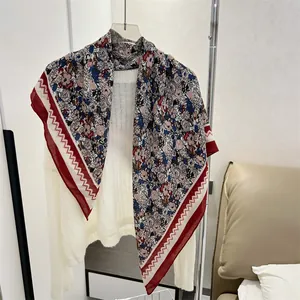 Close-up of a floral print cotton-linen square scarf draped over a white sweater
