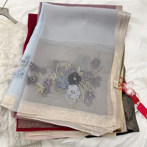 Close-up of silk blend scarf featuring elegant floral embroidery and sheer texture