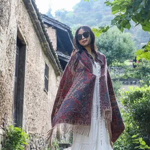 Woman wearing an ethnic paisley pattern thick shawl in a scenic outdoor setting.
