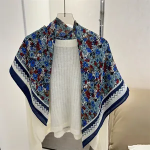 Floral cotton linen square scarf draped over a white sweater detail view