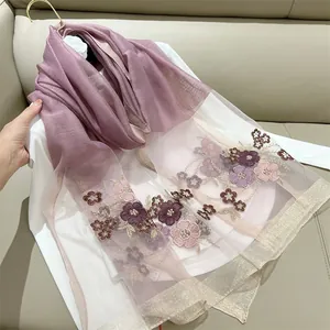 Close-up detail of elegant begonia floral embroidery on a purple silk blend sheer scarf.
