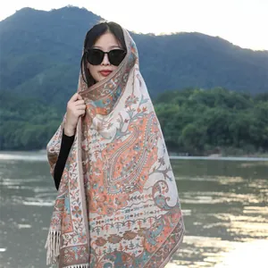 Detailed view of an ethnic paisley shawl with tassels worn by a model outdoors