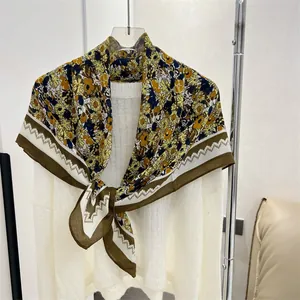 Detailed shot of yellow and brown floral cotton-linen square scarf on a white sweater