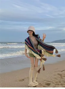 Model mit böhmischem Ethno-Strickschal mit bunten Quasten für Reisefotos am Strand im Freien