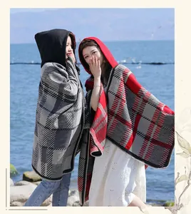 Models wearing red and grey vintage plaid hooded ponchos in a scenic outdoor setting