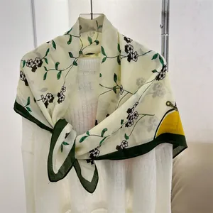 Close-up detail of an elegant floral cotton-linen square scarf tied over a white sweater