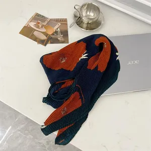 Detailed view of pleated cotton linen scarf with large floral patterns on marble surface
