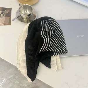Elegant black and white striped pleated cotton linen square scarf on a white marble desk