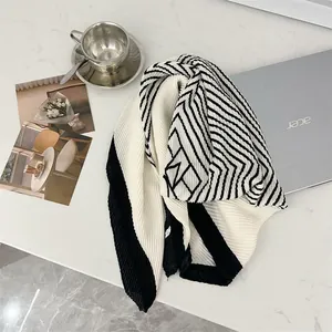 Top view of a pleated black and white 90cm square scarf styled on a marble desk
