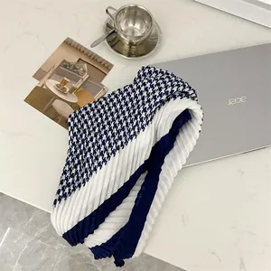 Detailed shot of a blue and white pleated houndstooth scarf on a marble table