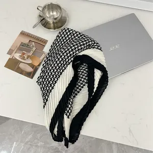 Close-up of black and white houndstooth pleated scarf on a modern desk