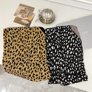 Detail view of two pleated leopard print square scarves with fine accordion texture