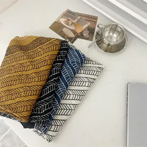 Close-up of pleated cotton linen square scarves with leaf patterns in four colors