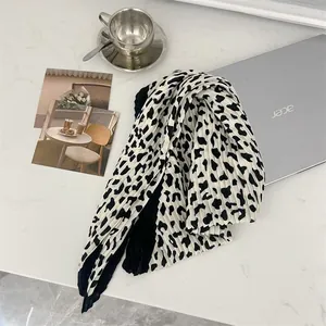 High-quality detail of a pleated leopard print cotton-linen square scarf on desk