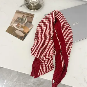 Detailed macro view of a red and white checkered pleated scarf with elegant crinkle texture