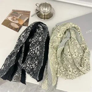 Detail view of pleated cotton linen scarves with intricate paisley patterns in two colors