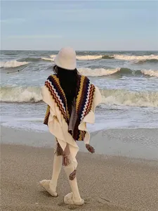 Rückansicht einer Frau im ethnischen Strick-Poncho mit Zickzack-Muster am Strand