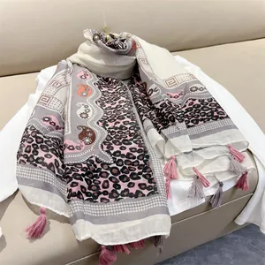 Detailed view of oversized ethnic leopard print scarf with tassels on soft white fabric