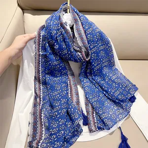 Detail view of blue and white floral cotton linen scarf featuring elegant tassels