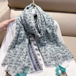 Detail view showing the delicate blue ethnic floral pattern and tassels on the scarf