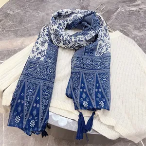Detail of vintage blue and white floral scarf with elegant tassels on white sweater.
