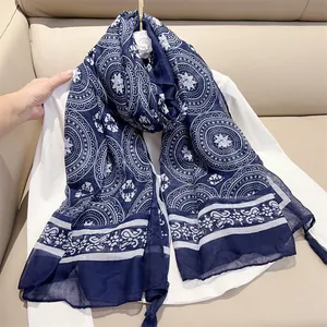 Detailed view of an elegant blue and white paisley print scarf with fringe tassels detail