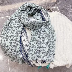 Close-up detail of a floral patterned cotton linen scarf draped over a white ribbed sweater