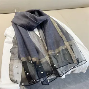 Detail view of grey faux silk scarf featuring white pearl embellishments and gold trim
