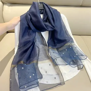 Detail showing elegant pearl embellishments and gold glitter border on navy blue silk-like scarf