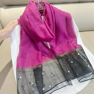 Detail view of fuchsia silk scarf with black mesh, pearls and gold trim.