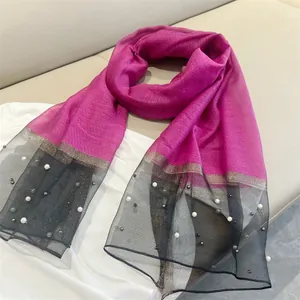 Close-up of elegant magenta faux silk scarf with pearl-embellished black mesh ends.