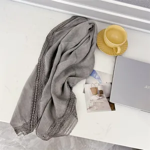 Λεπτομέρεια γκρι βαμβακερού κασκόλ με δαντέλα σε λευκό γραφείο με διακοσμητικά