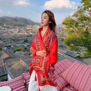 Red ethnic style cotton linen shawl with tassels shown in a scenic outdoor setting