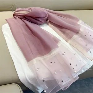 Detailed view of elegant pink faux silk scarf with pearl accents and gold borders