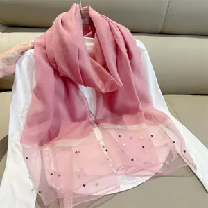 Detail view of pink faux silk scarf with elegant pearl bead accents and mesh hem.