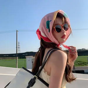 Detalle de un pañuelo de algodón y lino con flores rosas usado como bandana chic al aire libre