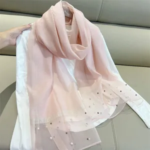 Elegant detail of a pink faux silk scarf with decorative pearls and a sheer glittery border
