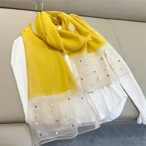 Close-up of yellow faux silk scarf featuring sheer ends adorned with elegant pearls