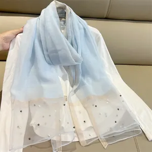 Close-up detail of elegant light blue faux silk scarf featuring pearl and lace trim