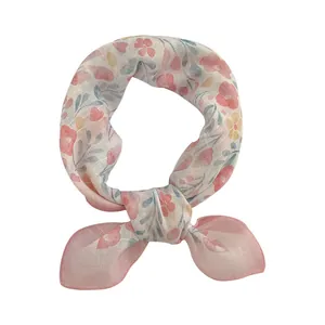 Detalle de un pañuelo cuadrado con estampado floral suave anudado de forma elegante
