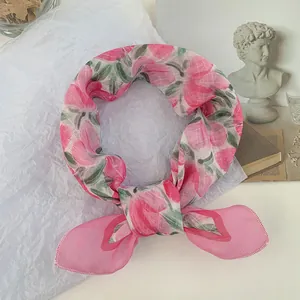 Primer plano de un pañuelo cuadrado con estampado floral rosa y detalles de dobladillo